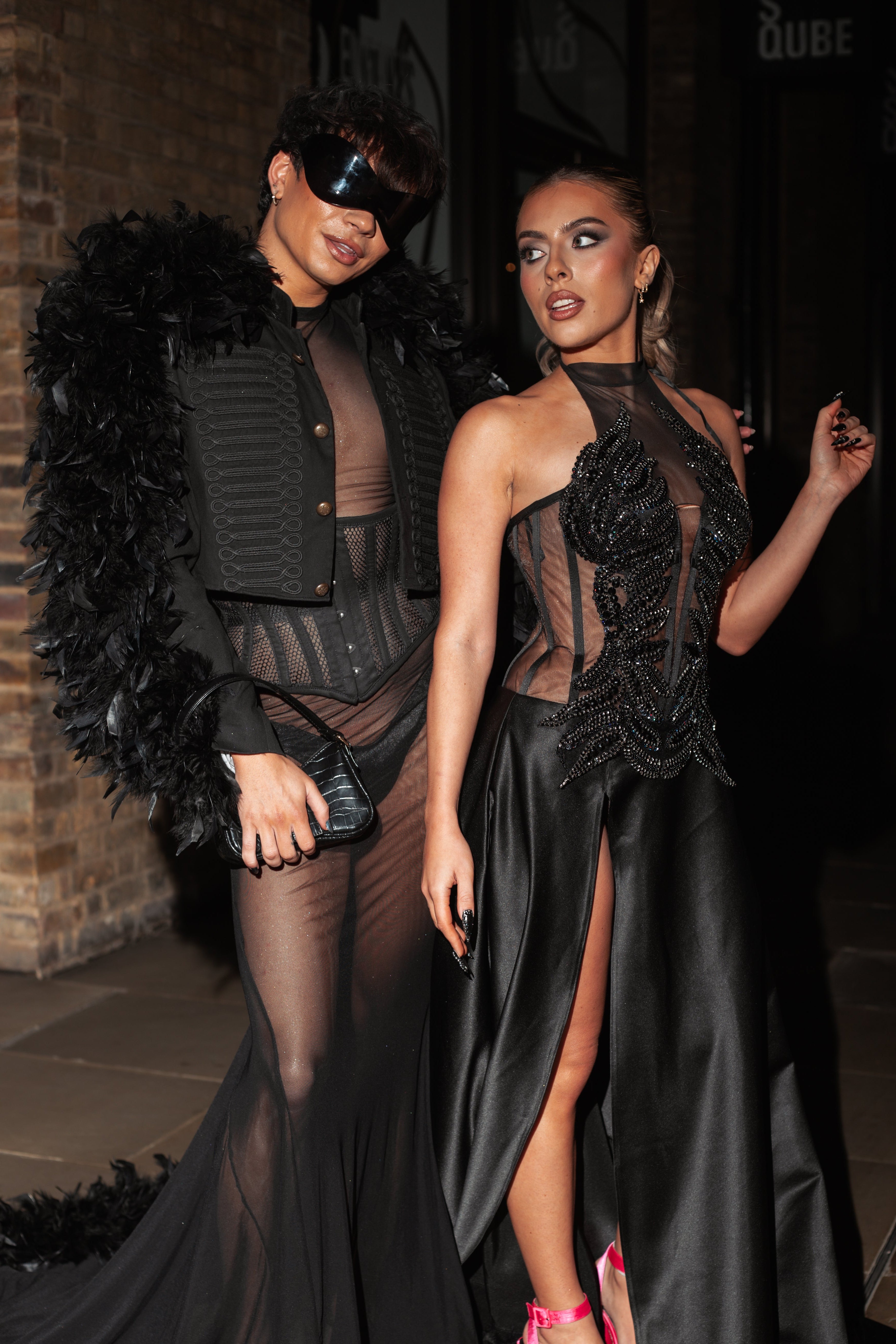 Sam Ashby and Nancy Nocerino Wearing bespoke kingfisher couture black evening gowns with feathered details standing at London Fashion Week Feb 2026